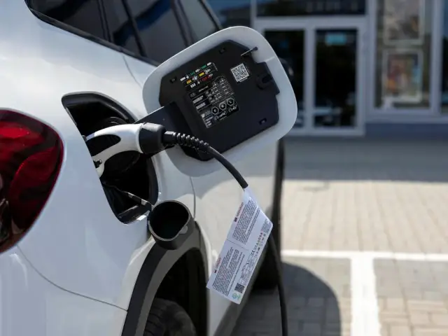 Biały samochód podłączony do ładowania. To przyszłość motoryzacji, czyli przerabianie samochodów na elektryczne.