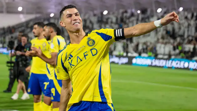 Uśmiechnięty Cristiano Ronaldo w żółtej koszulce Al Nassr, świętujący sukces. Jego zarobki w Arabii Saudyjskiej budzą podziw.
