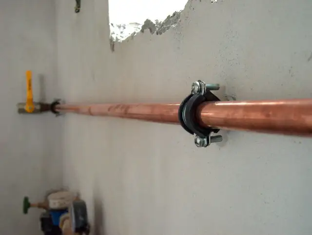 Miedziana rura gazowa, zamocowana obejmą. W tle żółty zawór. Jaka średnica rury do gazu ziemnego?