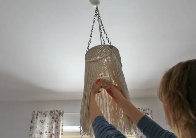 Kobieta montuje oprawkę żarówki w lampie ze sznurka. Dowiedz się, jak zrobić lampę ze sznurka krok po kroku.