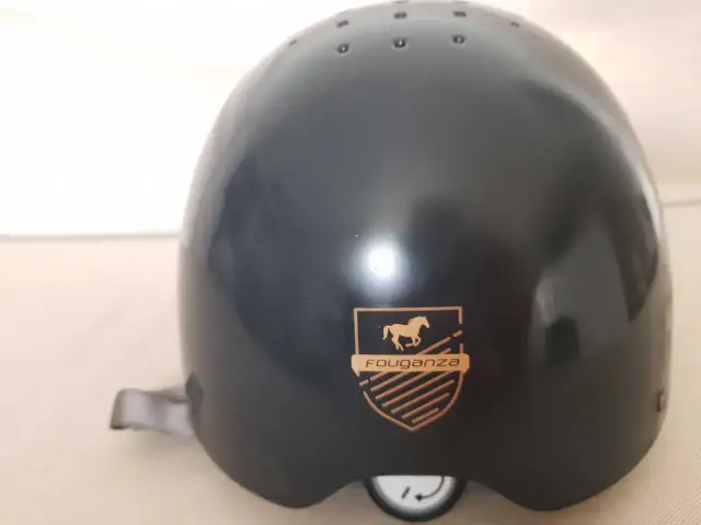 Czarny kask jeździecki Fouganza z logo konia i tarczą.