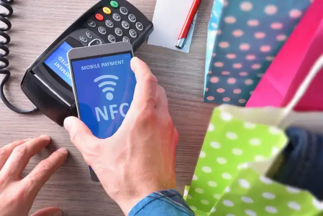 Zbliżasz telefon do terminala płatniczego, by zapłacić zbliżeniowo. To właśnie co to NFC – technologia, która ułatwia płatności mobilne.