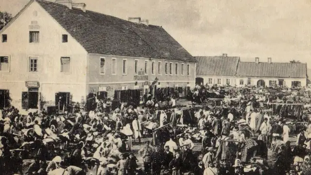 Tłum ludzi na targu w Biłgoraju, jakby żywcem wyjęty z legendy o tym mieście. W tle budynki i stragany.