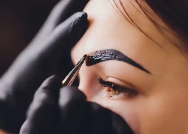 Stylist aplikuje hennę na brwi. Zastanawiasz się, ile kosztuje henna?