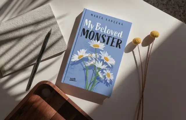 Okładka książki "My Beloved MONSTER" Marty Łabeckiej, z motywem stokrotek. To piękna miłość książka dla dzieci, która zachwyci najmłodszych.