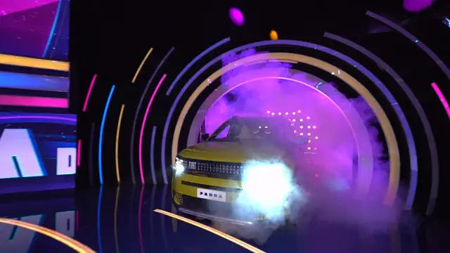 Żółty Fiat Panda wyjeżdża z dymu i świateł w kole fortuny.