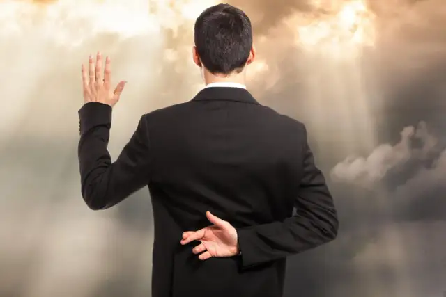 Mężczyzna w garniturze podnosi rękę do przysięgi, drugą rękę z założonymi palcami trzyma za plecami. Oto jak postępować z hipokrytą.