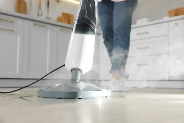 Mop parowy w akcji, para wydobywa się z urządzenia, czyszcząc podłogę.
