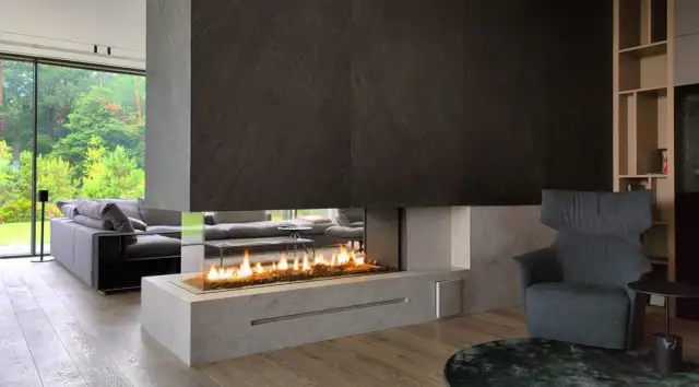 Nowoczesny salon z panoramicznym oknem i wkładem elektrycznym do kominka, tworzącym przytulną atmosferę.