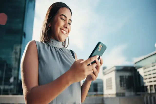 Uśmiechnięta kobieta sprawdza na telefonie, jak sprawdzić ile zostało internetu.
