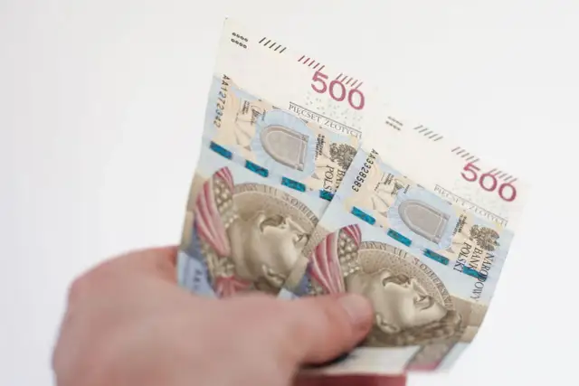 Dłoń trzyma polskie banknoty 500 złotych.