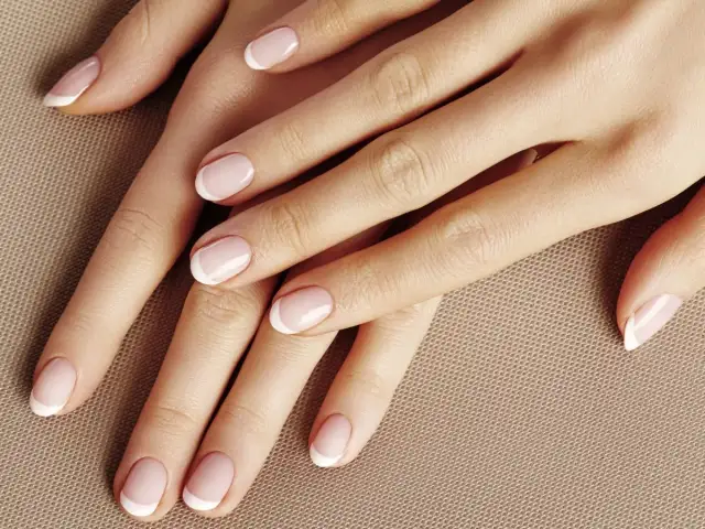 Dłonie z perfekcyjnym manicurem french kombinowany. Delikatny róż i biel podkreślają elegancję.
