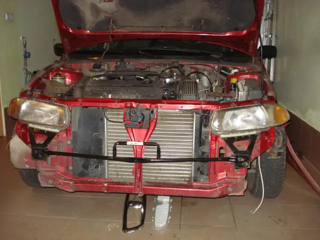 Czerwony samochód z otwartą maską, widoczny przód zdemontowanego zderzaka. Jak zdemontować zderzak przedni bez urwania zaczepów?