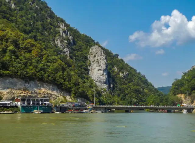 Wielka twarz wyrzeźbiona w skale, symbolizująca Żelazną Bramę, góruje nad rzeką.