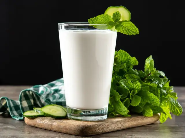 Szklanka orzeźwiającego ayranu, napoju jogurtowego, z plasterkami ogórka i miętą. Idealny na upalne dni.