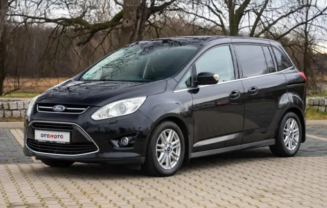 Czarny Ford C-Max na tle drzew. Wiele osób szuka pozytywnych ford c max opinie przed zakupem.