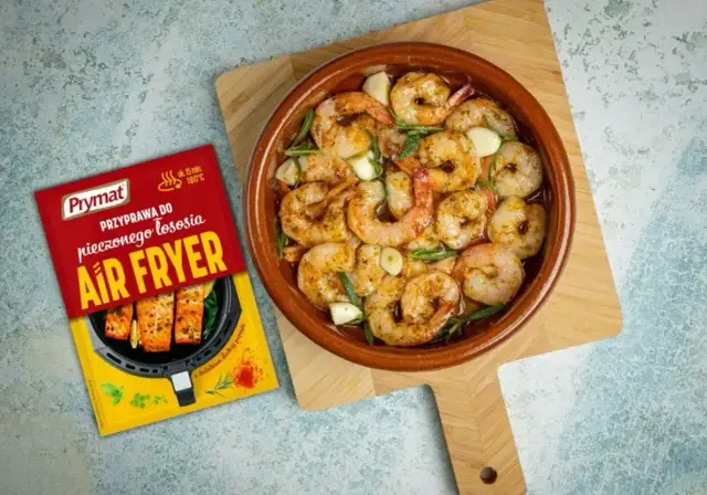 Soczyste krewetki z czosnkiem i ziołami w naczyniu, obok przyprawa Prymat do Air Fryer.
