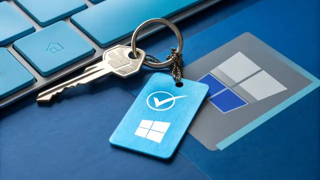 Klucz do aktywacji systemu Windows 11, symbolizujący legalną licencję, leży na niebieskiej klawiaturze.
