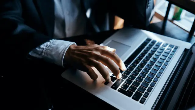 Dłoń na klawiaturze laptopa, szukamy informacji, jak sprawdzić ile ma się lat pracy.