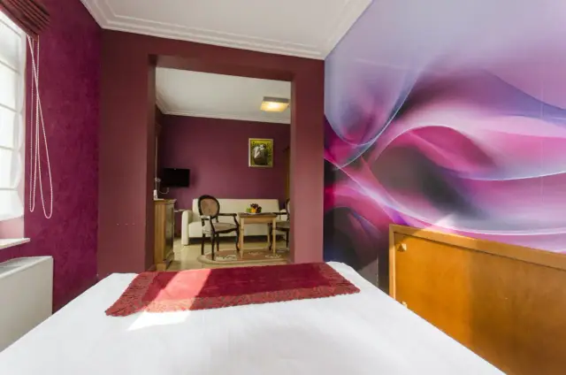 Pokój w hotelu Apollo Darłówko z kolorową tapetą i wygodnym łóżkiem.