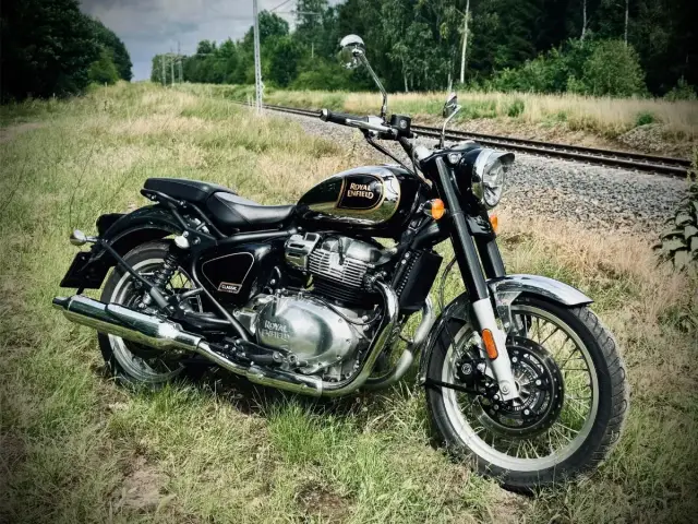 Czarny Royal Enfield Classic 650 lśni chromem przy torach kolejowych. Gotowy na podróż.