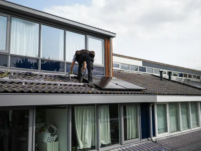 Instalator na dachu montuje panele fotowoltaiczne. Kluczowe jest, jak obliczyć przekrój kabla do mocy, by instalacja działała bezpiecznie i efektywnie.