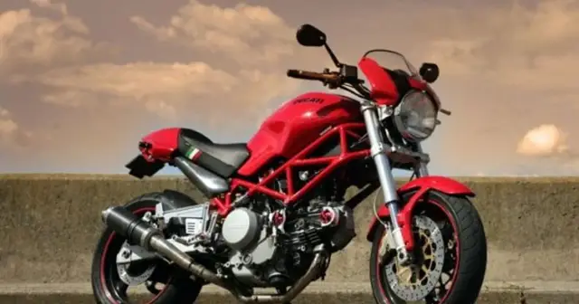 Czerwony Ducati Monster 600 z charakterystyczną kratownicową ramą, gotowy do jazdy pod zachmurzonym niebem.
