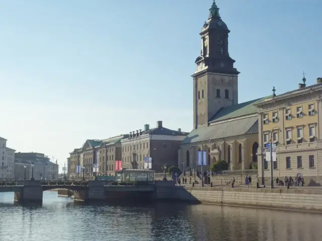 Malowniczy widok na kanał i zabytkowe budynki w jednym z miast Szwecji. W tle dumnie wznosi się wieża kościelna.