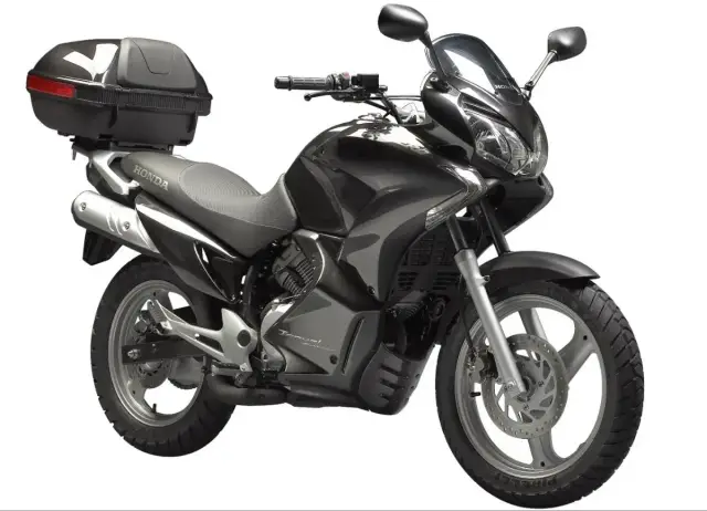 Czarny motocykl Honda Dominator z kufrem na bagaż, gotowy na dalekie podróże.