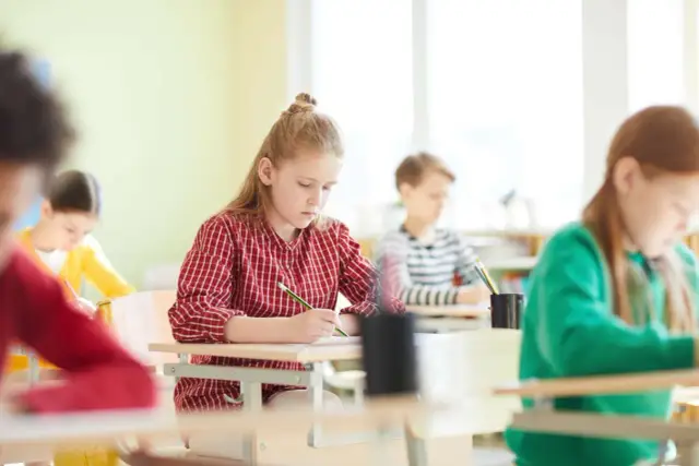Dzieci piszą testy w szkole. Zastanawiają się, czy ocena z diagnozy wlicza się do średniej.