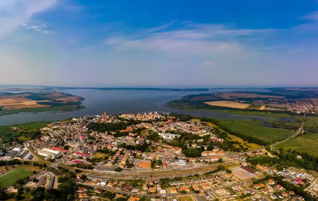 Widok z lotu ptaka na Kamień Pomorski. Miasto z czerwonymi dachami, port, jezioro i pola uprawne. Odkryj kamień pomorski atrakcje!