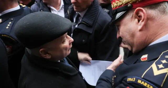 Straż marszałkowska w mundurach rozmawia z mężczyzną w czarnym berencie. Jeden z funkcjonariuszy pokazuje dokument.