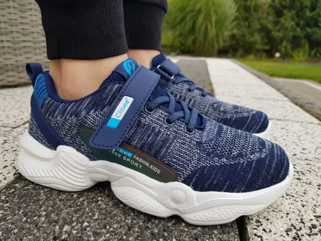 Granatowe buty sportowe dla dziecka z rzepem i sznurówkami. Dowiedz się, ile większe powinny być buty dla dziecka, by zapewnić komfort.