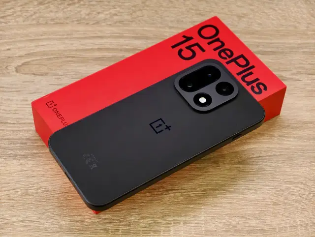 Czarny telefon OnePlus 15 na czerwonym pudełku.