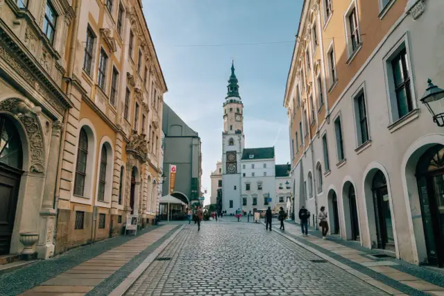Ulica w mieście Wałbrzych z wieżą ratuszową i brukowanym rynkiem.
