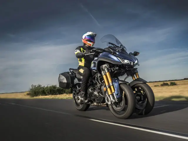 Kierowca na motocyklu Yamaha Niken GT przemierza wiejską drogę.