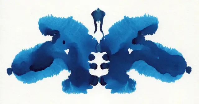 Symetryczny, niebieski plama tuszu na białym tle, przypominająca motyla lub nietoperza. To klasyczny test rorschacha.