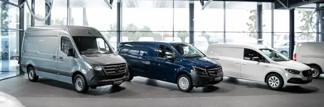 Trzy dostawcze samochody marki Mercedes-Benz: szary, granatowy i biały, stoją w salonie.