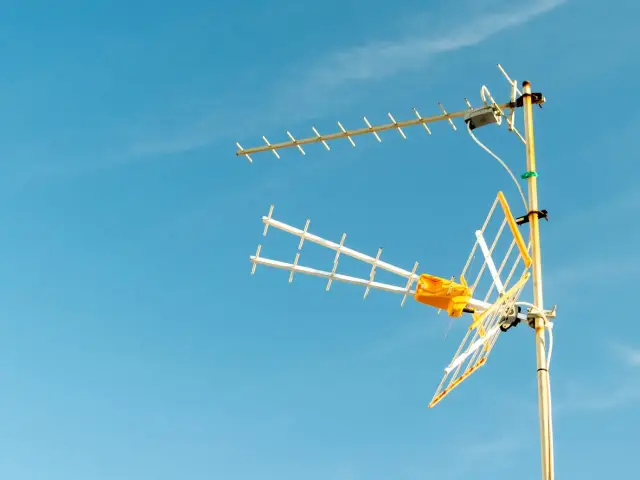 Antena telewizyjna z żółtym wzmacniaczem na maszcie, gotowa do podłączenia.