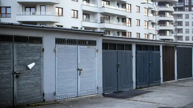 Rząd garaży z szarymi, drewnianymi i metalowymi wrotami. Zastanawiasz się, ile kosztuje wymurowanie garażu?