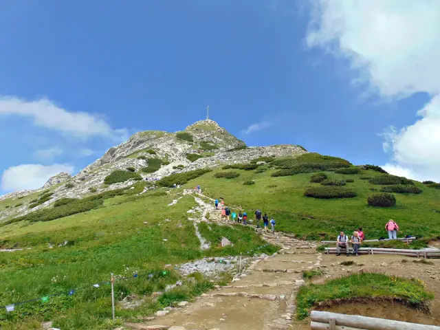Tłum turystów wspina się kamienistym szlakiem na szczyt Giewontu, by zobaczyć, ile ma Giewont.