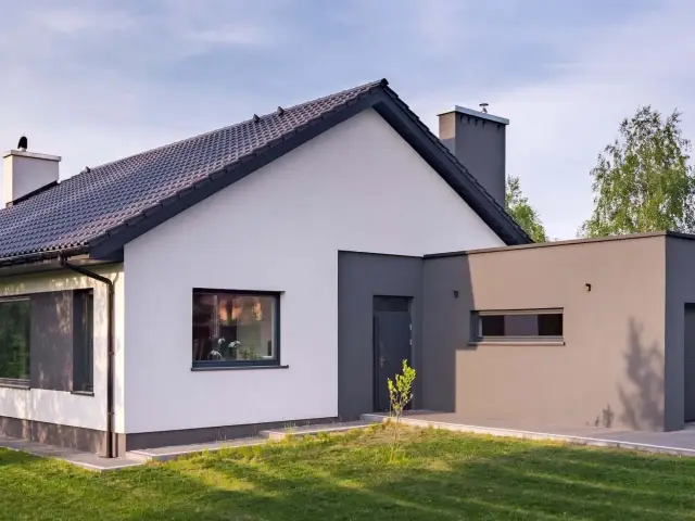 Nowoczesny dom z białym i grafitowym tynkiem. Elewacja domu prezentuje się elegancko, podkreślając jego architekturę.