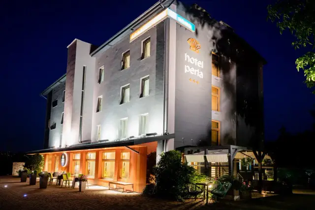 Hotel Perła Kraków nocą. Elegancki budynek z podświetlanym logo i oknami.