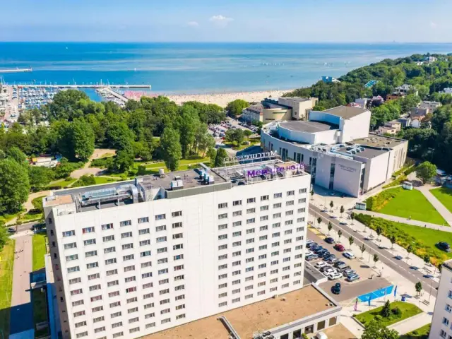 Widok z lotu ptaka na hotel Mercure Gdynia z widokiem na morze, plażę i marinę.