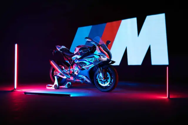 Sportowy motocykl BMW M1000R w neonowym świetle, z logo M w tle.