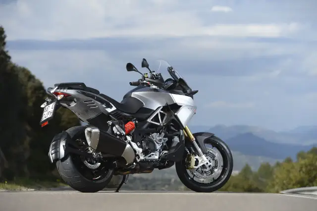 Srebrny motocykl Aprilia Caponord 1200 na tle górskiego krajobrazu. Poznaj jego aprilia caponord 1200 dane techniczne.