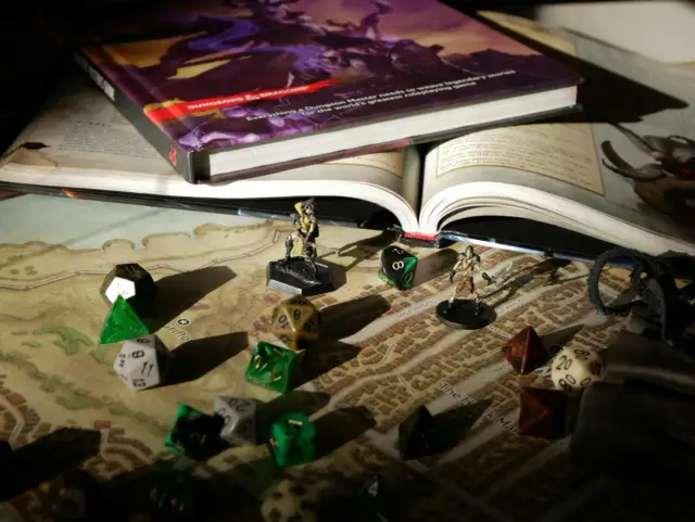 Księga D&D, kostki i figurki na mapie - wszystko gotowe do epickich **gier fabularnych**.