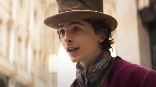 Młody Willy Wonka w kapeluszu i kolorowym szaliku, zapowiadający film "Charlie i fabryka czekolady 2023".