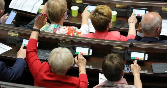 Posłowie w Sejmie głosują, podnosząc ręce i naciskając przyciski na tabletach. Trwa reasumpcja głosowania.