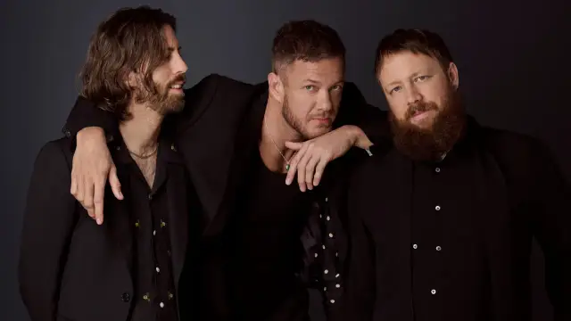 Trzech członków Imagine Dragons w czarnych strojach, gotowych na koncert.